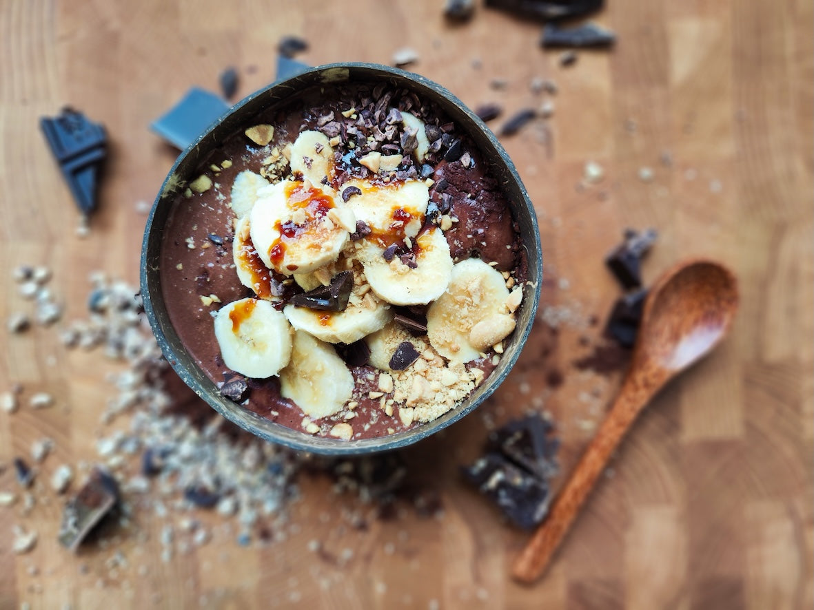 Chocoladebowl met banaan, pindastukjes en cacaonibs op een chocoladebasis
