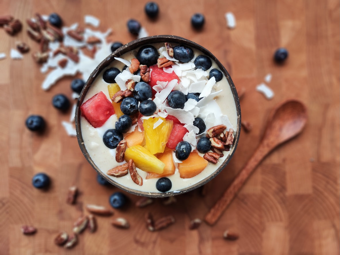 Tropische fruit bowl met kokosbasis, ananas, meloen, blauwe bessen, pecannoten en kokosvlokken
