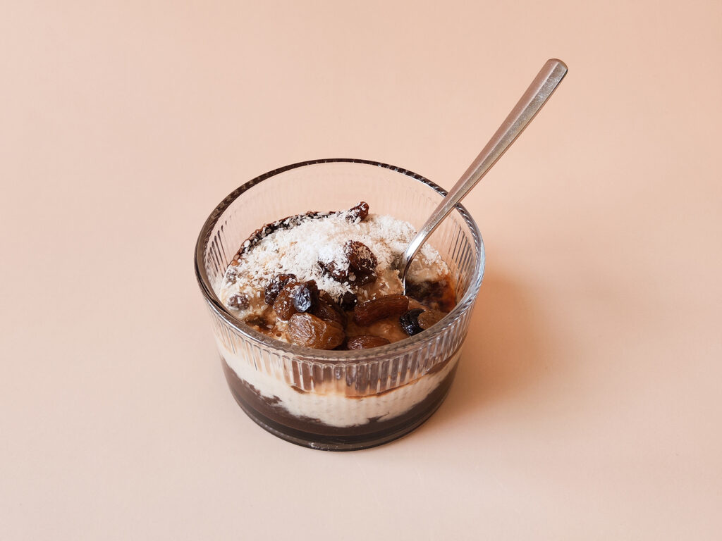 Chocolade vanille rijst toetje met rozijnen en kokosrasp in glazen dessertbakje